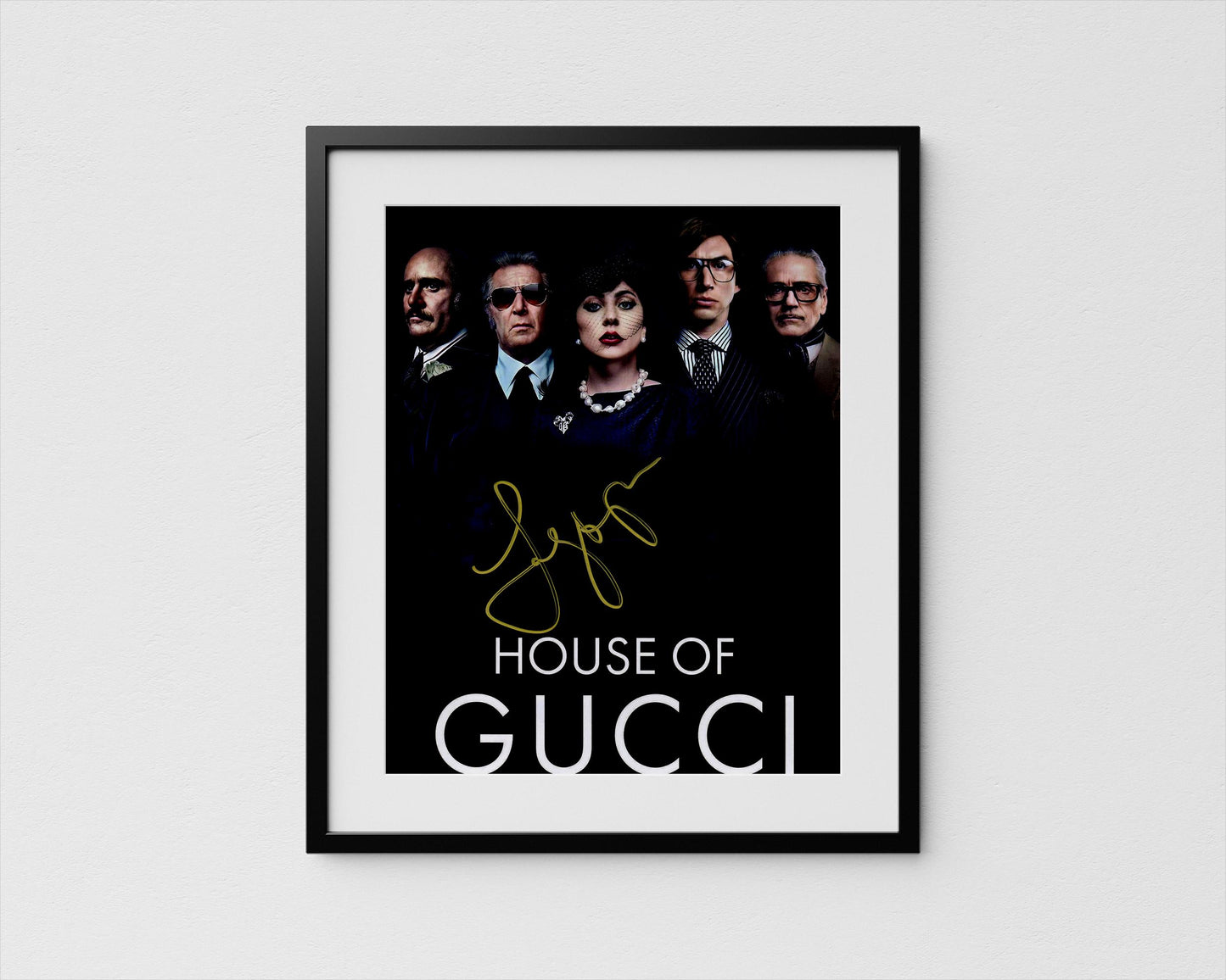 The image is a framed poster featuring the cast of the movie "House of Gucci".
