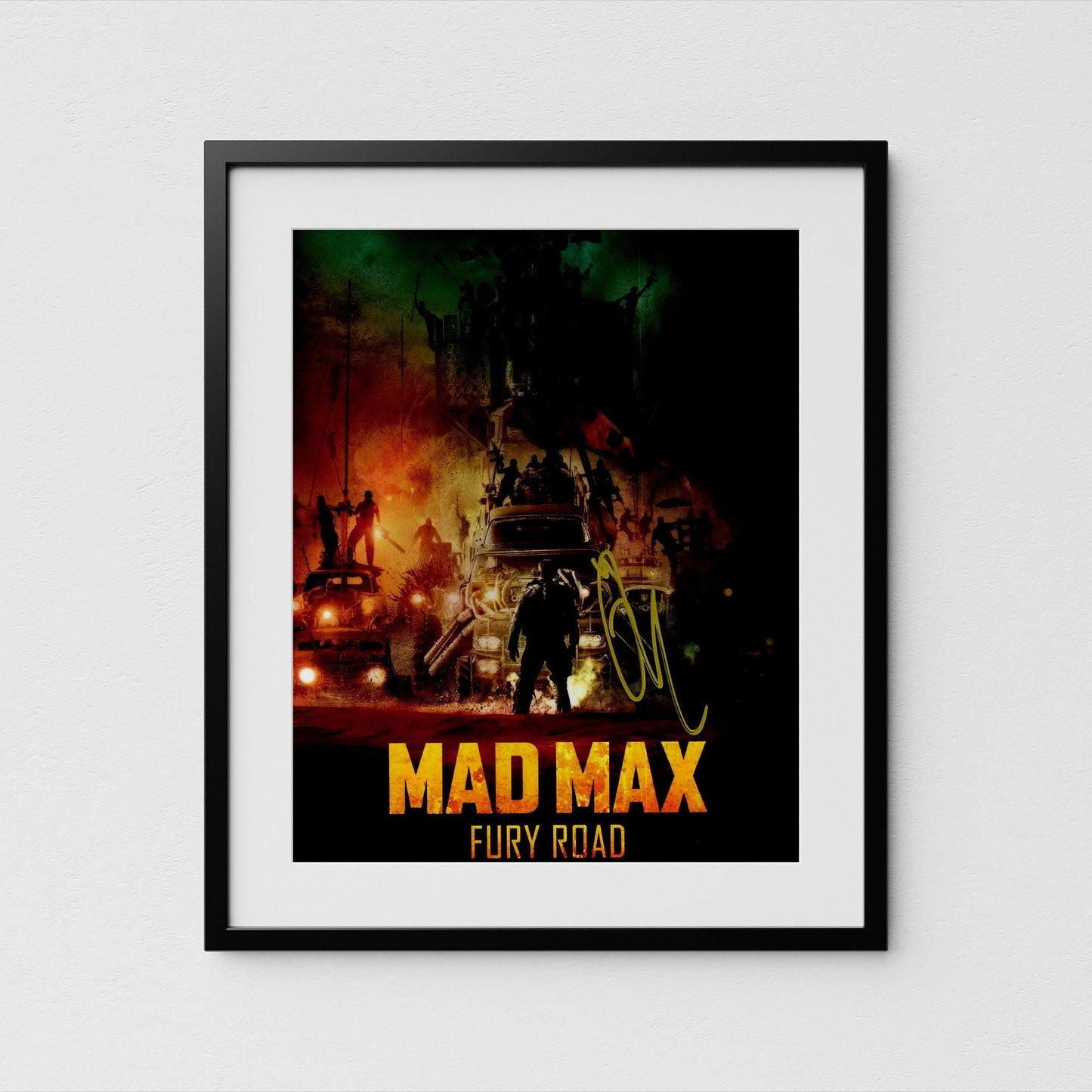 The image is a framed poster or artwork featuring a scene from the movie &quot;Mad Max: Fury Road&quot;. The poster has a dark, dramatic background with various vehicles and people, creating a sense of chaos and tension. The title &quot;Mad Max: Fury Road&quot; is prominently displayed in large, bold letters at the bottom of the poster.