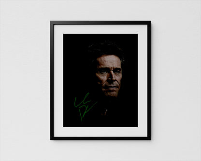 A framed portrait of Willem Dafoe with a serious expression, set against a dark background.