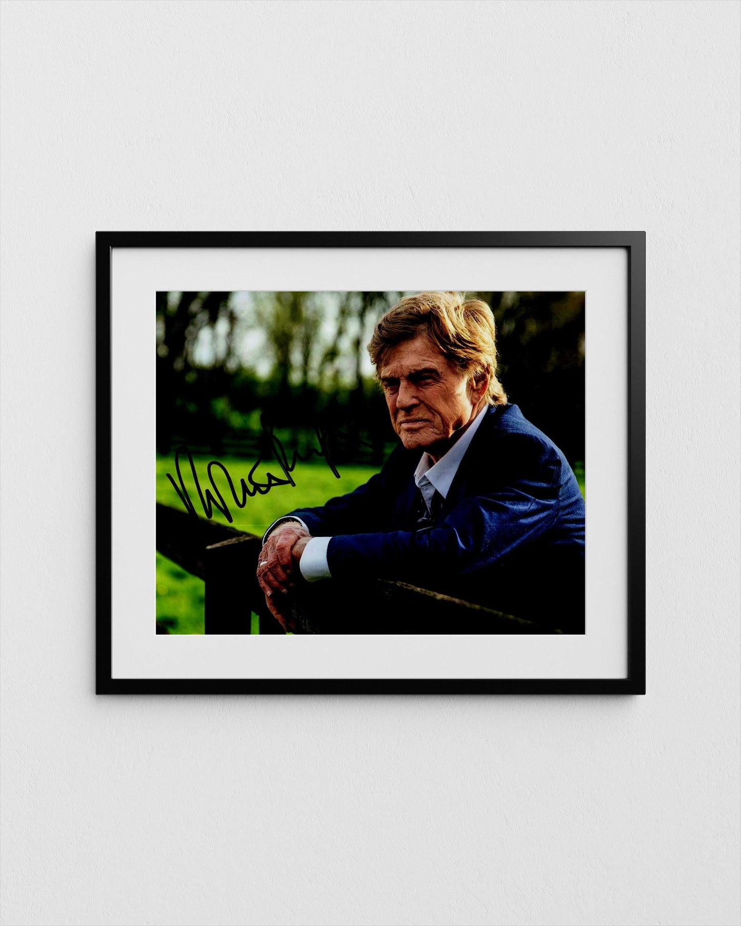 A framed photograph of a man in a suit, sitting outdoors and looking directly at the camera with a serious expression.