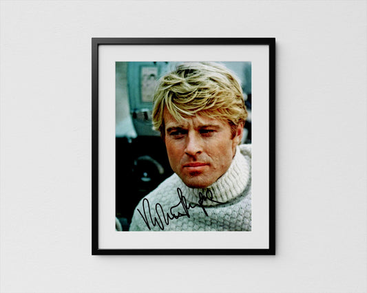 A framed photograph of a man with blonde hair wearing a white sweater, looking pensively at the camera.