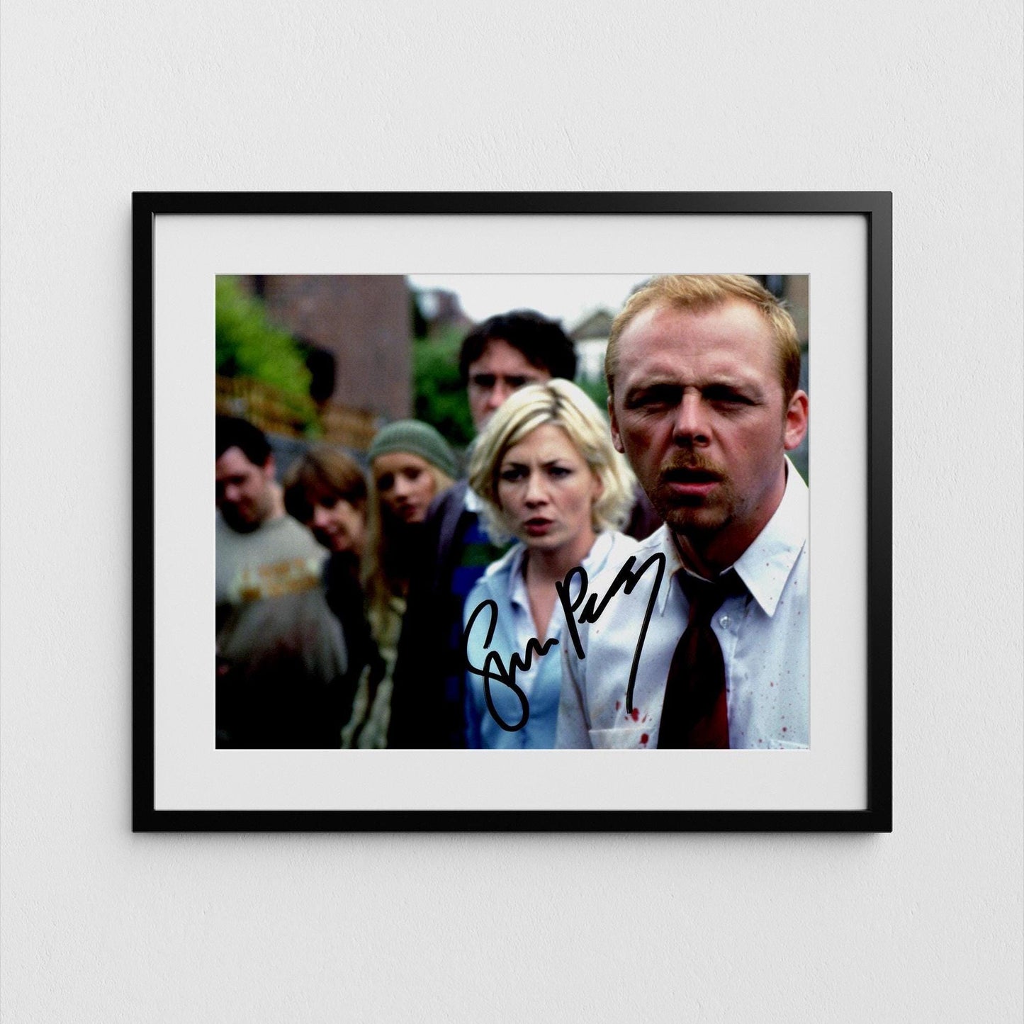 The image is a framed photograph of a group of people, with a man in a suit and tie prominently featured in the foreground.
