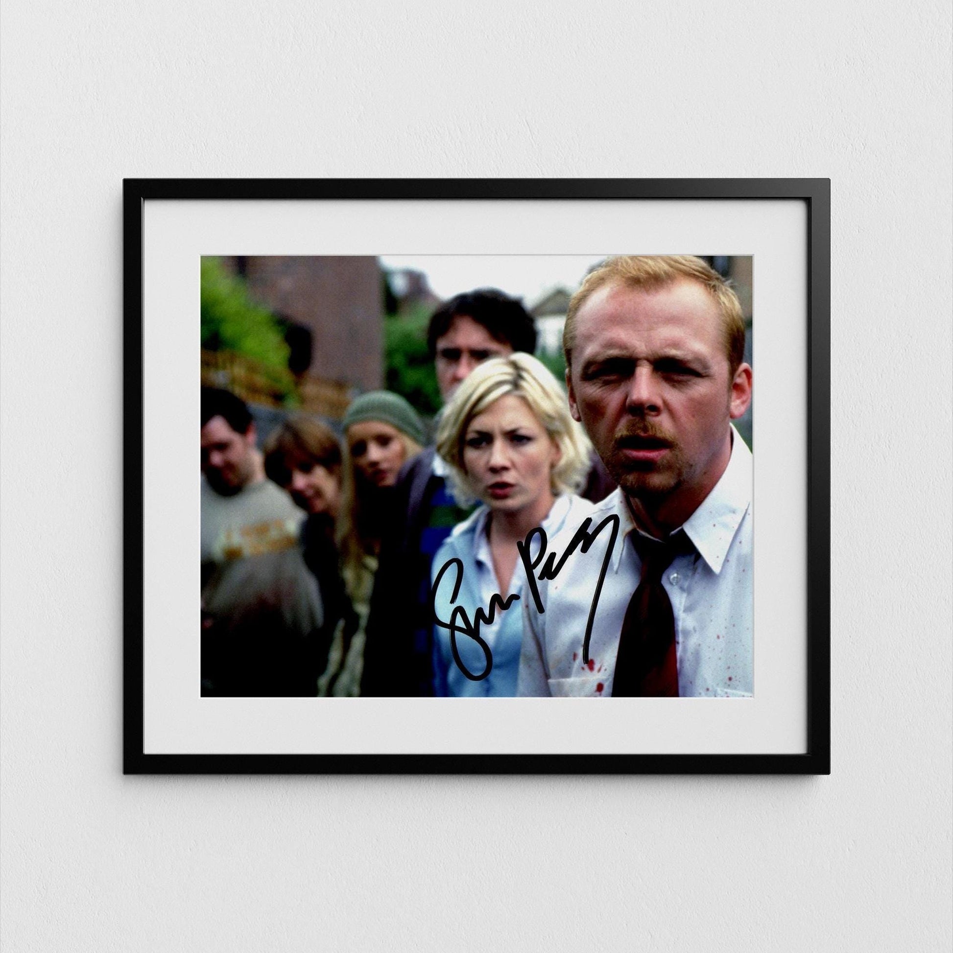 The image is a framed photograph of a group of people, with a man in a suit and tie prominently featured in the foreground.