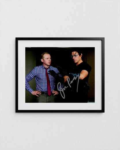 tom cruise and simon pegg, one wearing a blue plaid shirt and the other wearing a black shirt, posing together in a framed photograph.