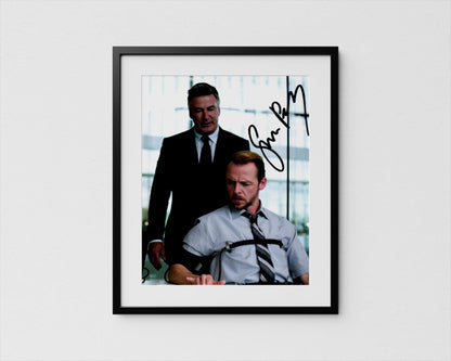 The image is a framed photograph of two men, one standing and one sitting, both wearing suits and ties. The man sitting is looking down, while the standing man appears to be in a more serious or contemplative mood.