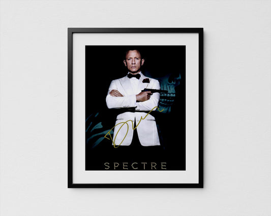 A framed poster featuring a man in a tuxedo with his arms crossed, holding a gun, against a dark background with a skull and green foliage.