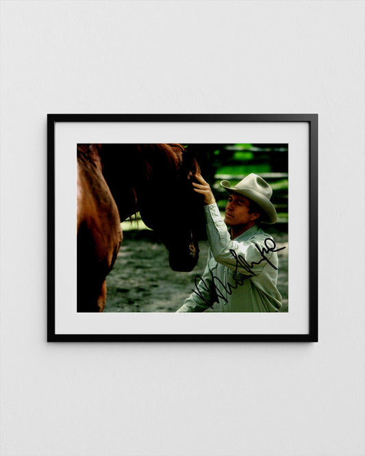 A framed photograph of a man in a cowboy hat tenderly petting a horse&#39;s head.